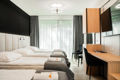a hotel room with three beds and a desk at Grand Chotowa Hotel Spa & Resort in Chotowa