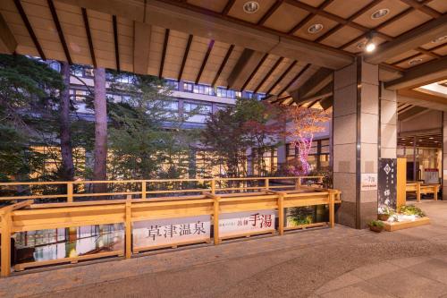 a building with a wooden fence in front of it at Hotel Sakurai in Kusatsu