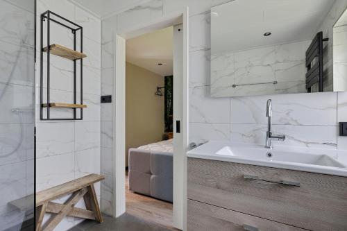 a bathroom with a sink and a bed at Comfortabel 2- persoons vakantiehuis nabij bos in Drenthe in Schoonoord