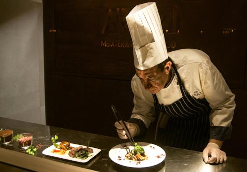 a chef preparing a plate of food on a counter at Hotel Federico II Central Palace in Palermo