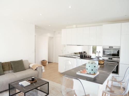 une cuisine et un salon avec un canapé et une table dans l'établissement Deauville Riviera - Jardin face à la Plage, Proximité & Luxe Inégalé, à Deauville