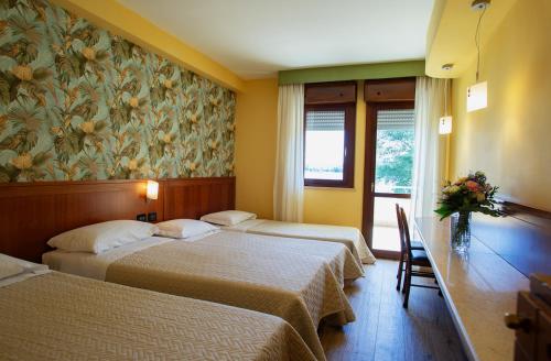 two beds in a hotel room with a floral wallpaper at Hotel Miralago in Piediluco