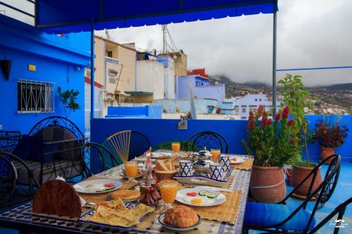 a table with food on top of a blue building at Casa Voyager 'secret garden terrace' in Chefchaouene