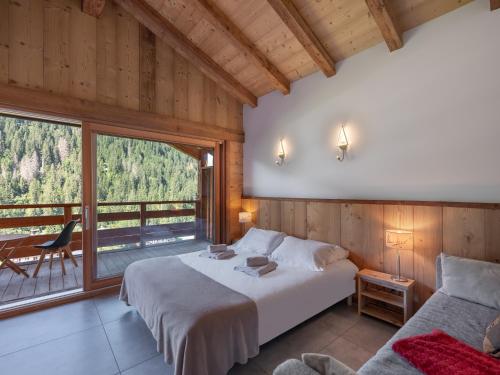 a bedroom with a bed and a large window at Chalet 1100 - Bo Immobilier Chatel - à mi-chemin du centre et du Linga - jacuzzi sauna et cheminée in Châtel