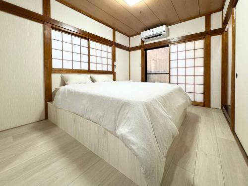 东京Family House 蕾 池袋徒步圈全新装修日式户建民宿的一间带窗户的房间里有一张白色床的卧室