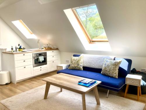un soggiorno con un divano blu e una cucina di The Loft at Craiglea a Pitlochry