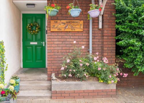 a green door on a brick house with flowers at Two Stylish Apartments Sleeps 10 BHX NEC in Coleshill