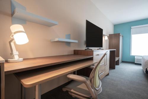 a room with a desk with a television and a chair at Home2 Suites by Hilton Fort Walton Beach Eglin AirForce Base in Fort Walton Beach