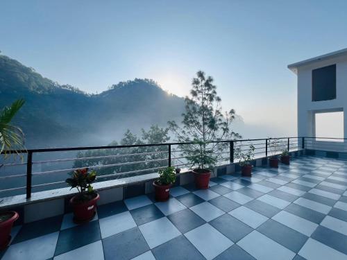 a balcony with potted plants and a view of the mountains at The Shalam Resort श्रीकृष्ण शरणं मम in Lansdowne