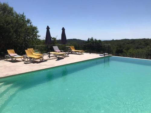 une grande piscine avec chaises et parasols dans l'établissement Maison de vacances 12 chambres et piscine, à Colognac