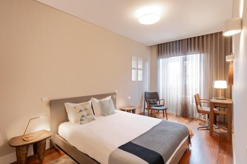 a hotel room with a bed and a desk and chairs at VIVA Aliados Spacious & Bright Flat in Porto