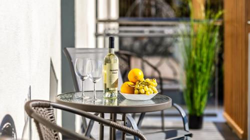 a table with a bottle of wine and a bowl of fruit at BURSZTYNOVA Apartamenty Piamola in Kąty Rybackie
