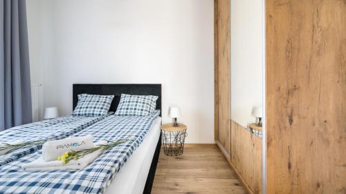 a bedroom with a bed with a blue and white checked blanket at BURSZTYNOVA Apartamenty Piamola in Kąty Rybackie
