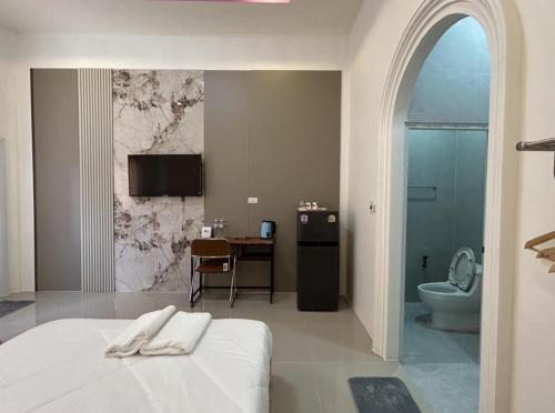 a bedroom with a bed and a bathroom with a toilet at Katthaleeya Resort คัทลียา รีสอร์ท in Kantharalak