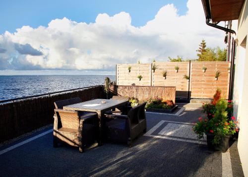 a patio with a table and chairs next to the water at Apartamenty 5 metrów od morza in Rewa