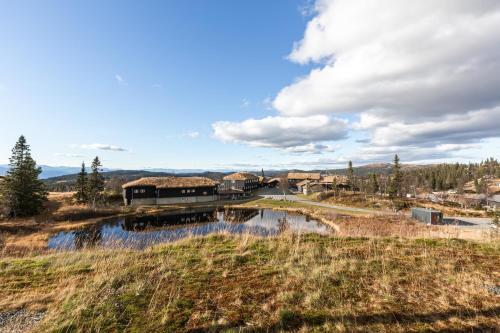 a house in a field next to a river at Naturopplevelser året rundt i Valdres Ski in out Panoramautsikt in Aurdal