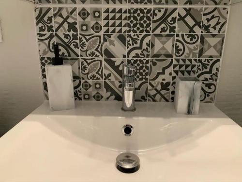 La salle de bains est pourvue d'un lavabo et de carrelage noir et blanc. dans l'établissement Le cocon T2 duplex 24 m2, à Niort
