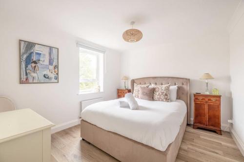 a bedroom with a bed with white sheets and a window at 3Bed, 2Bath Penthouse Near Windsor & Long Walk in Windsor