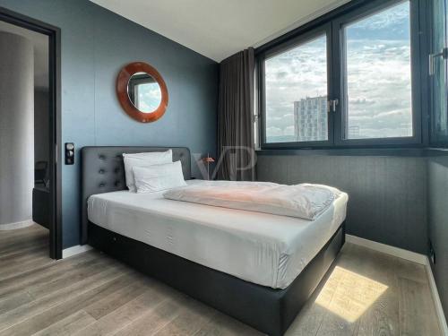 a bedroom with a bed with a mirror and two windows at Suites im Cloud in Stuttgart