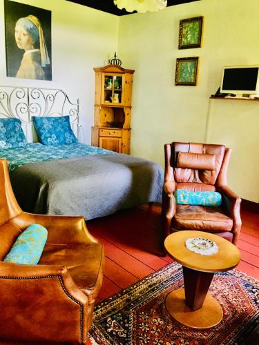 a bedroom with a bed and a chair and a table at Studio in farmhouse Close to Giethoorn in Kallenkote