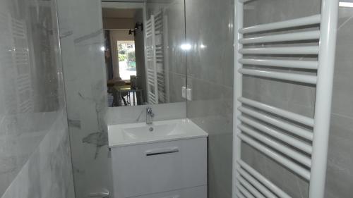une salle de bain blanche avec un lavabo et un miroir dans l'établissement Bas de villa prestations haut de gamme, à Vallauris