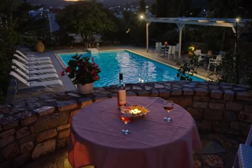 a table with a bottle of wine and glasses next to a swimming pool at Kamelia Villas in Votsi