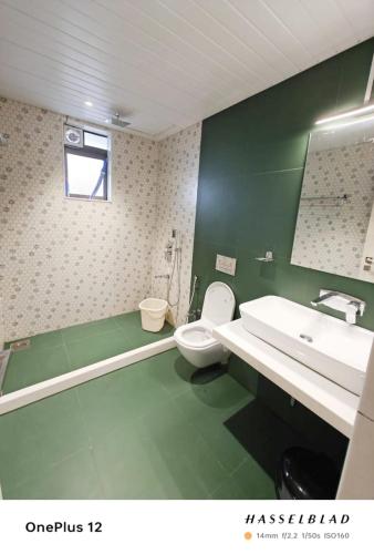 a green bathroom with a toilet and a sink at Mizzle Exotica Lonavala in Lonavala