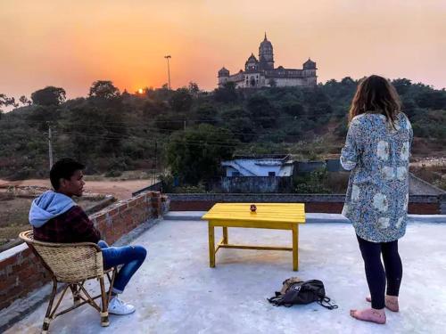 a woman standing next to a man sitting in a chair at Comfort and Cozy in Orchha