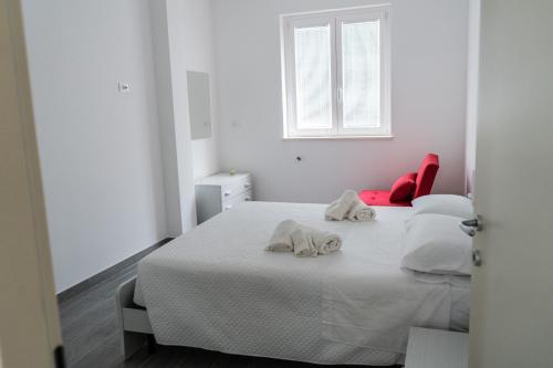 a white bedroom with two beds and a red chair at Moon Valley Holiday Home in Lauria