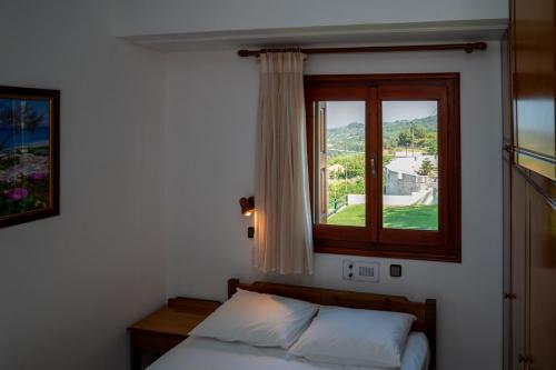 a bedroom with a bed and a window at Giannakos Apartments in Ydroússa