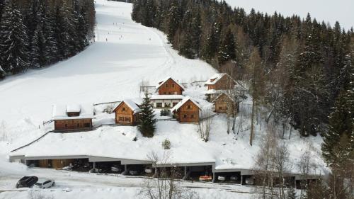 a house covered in snow on a snow covered slope at Hüttendorf Schlögelberger in Sankt Margarethen im Lungau