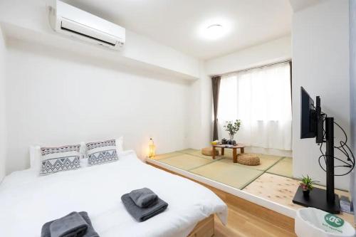 a white bedroom with a bed and a tv at 今和Hotel in Tokyo