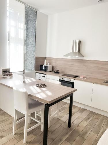 une cuisine avec une table en bois et des armoires blanches dans l'établissement Le Petit Cocon - Pause douceur, à Cambrai