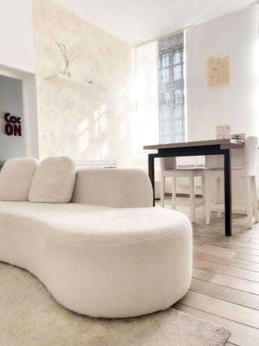un salon blanc avec un canapé blanc et une table dans l'établissement Le Petit Cocon - Pause douceur, à Cambrai