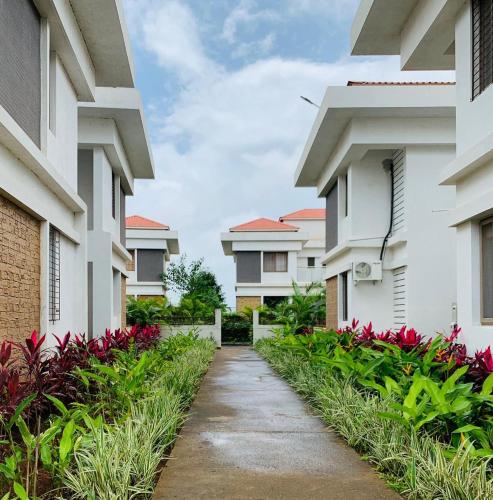 a walkway between two apartment buildings with red flowers at Mizzle Exotica Lonavala in Lonavala