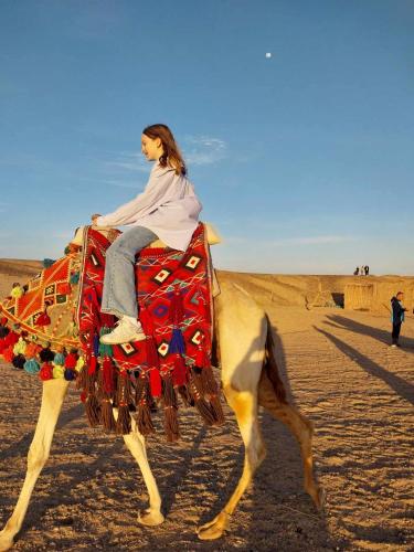 a woman riding a camel in the desert at Apadi camp in Port Ghalib