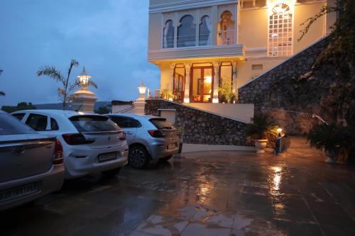 two cars parked in a parking lot in front of a house at Burj Baneria - A Boutique Homestay in Udaipur