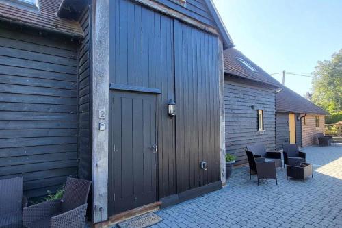 a building with a wooden door and some chairs at 2 Coopers Cottages, Bodiam, East Sussex in Bodiam