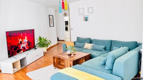 a living room with a blue couch and a tv at Charmant et cosy appartement à Créteil lac in Créteil
