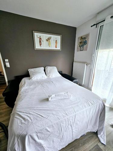 une chambre avec un grand lit blanc avec des draps blancs dans l'établissement Appartement avec parking privé, à Boussy-Saint-Antoine