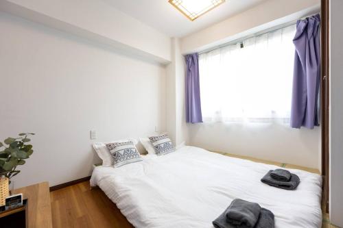 a bedroom with a bed and a window with purple curtains at 今和Hotel in Tokyo