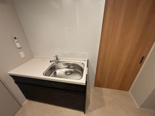 a silver sink in a bathroom with a wooden door at PORTA INN bentencho in Osaka