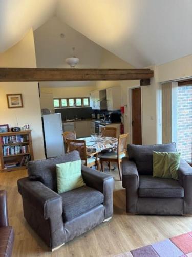 a living room with two chairs and a dining room at 3 Coopers Cottages, Bodiam, East Sussex in Bodiam