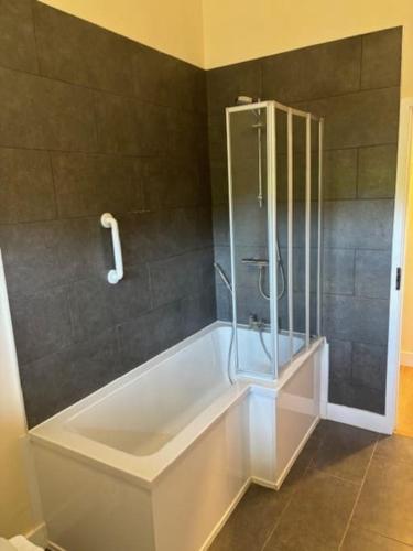 a bath tub with a glass shower in a bathroom at 3 Coopers Cottages, Bodiam, East Sussex in Bodiam