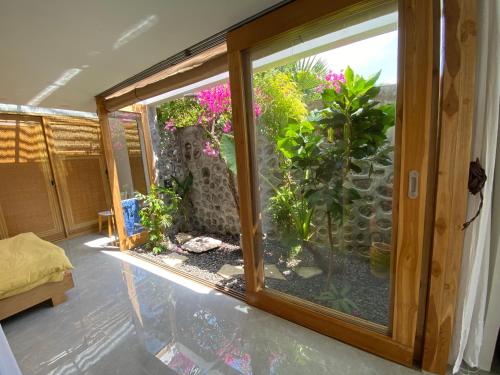 a room with a large glass window with plants in it at Green Villa Sambirenteng in Gretek