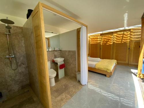 a bathroom with a toilet and a bed and a shower at Green Villa Sambirenteng in Gretek