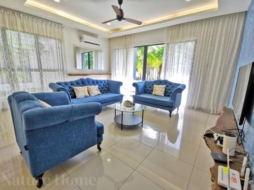 a living room with two blue couches and a tv at Nature Home 2 - Swiss Garden Resort Residences Beachfront Villa in Kuantan