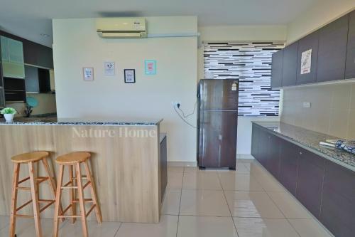 a kitchen with two bar stools and a refrigerator at Nature Home 2 - Swiss Garden Resort Residences Beachfront Villa in Kuantan