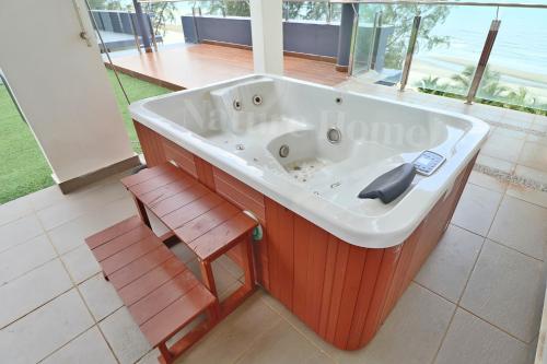a large bath tub with a bench and a chair at Nature Home 2 - Swiss Garden Resort Residences Beachfront Villa in Kuantan