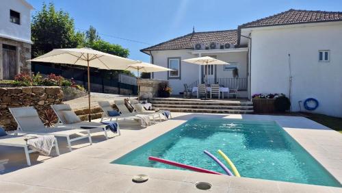 a pool with chairs and umbrellas next to a house at Casas São Tiago - Arouca, conforto e natureza in Arouca